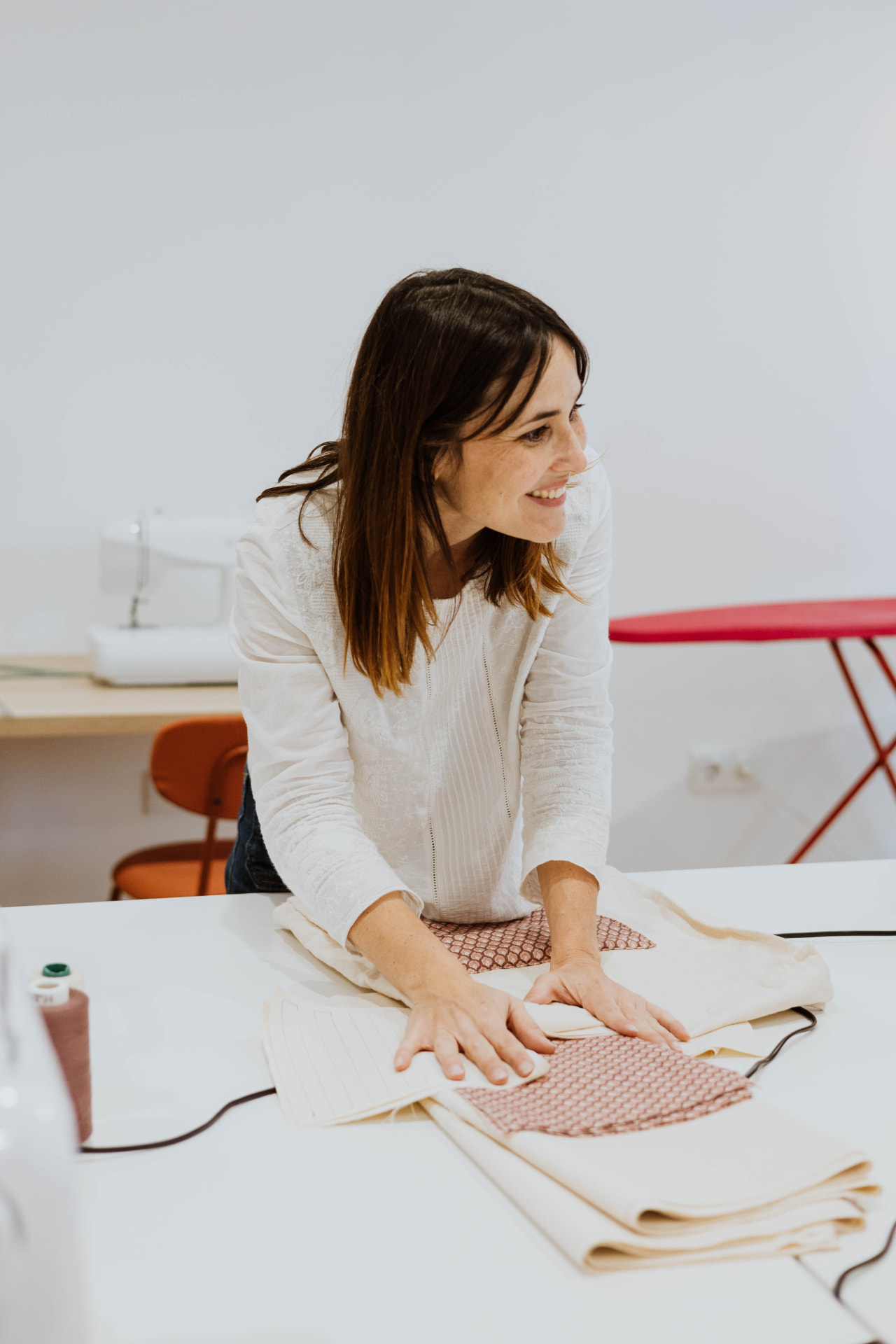 Alba Domene, creadora y profesora de Coser y Cantar, sonriendo ante la mesa de su taller de costura en Villena